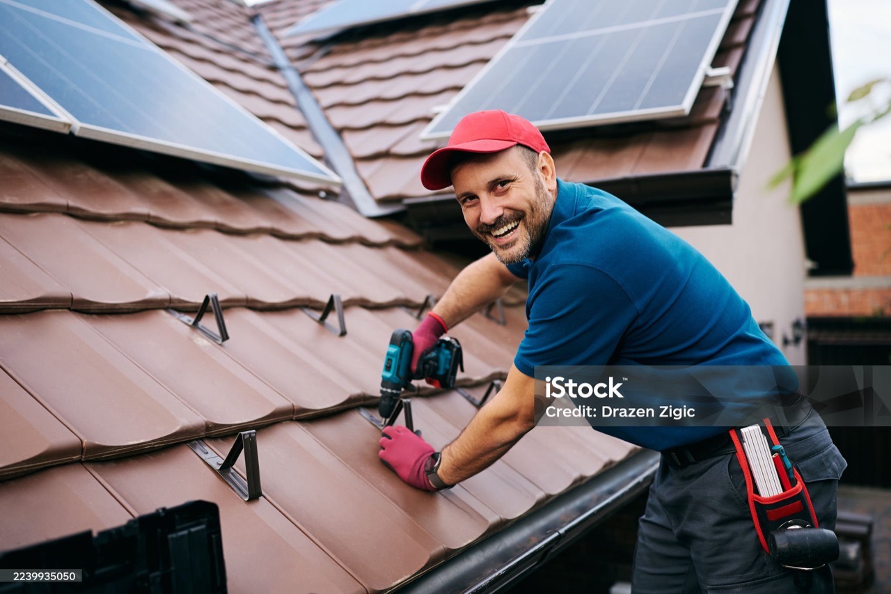 Dachdecker montiert eine Photovoltaik-Anlage auf einem Ziegeldach